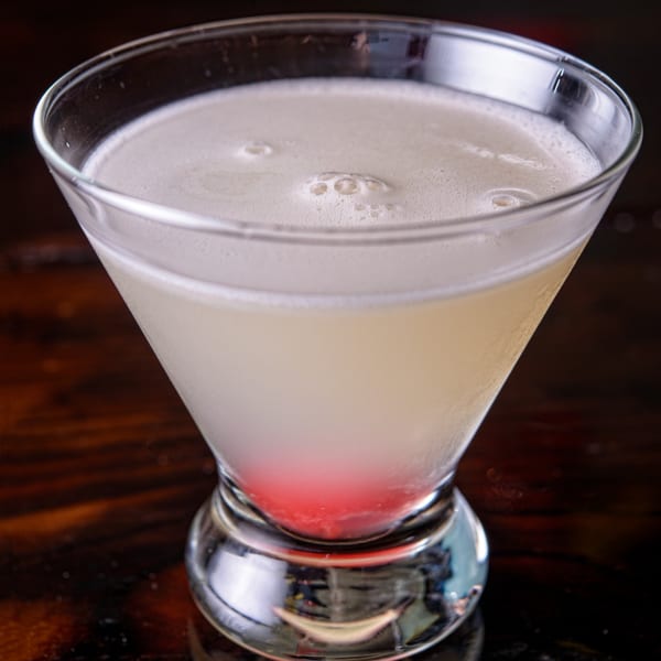 A Cuban cocktail with a foamy top and a red layer at the bottom, in a martini glass.